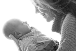 Langhaarige Mutter schaut hält Baby auf dem Arm